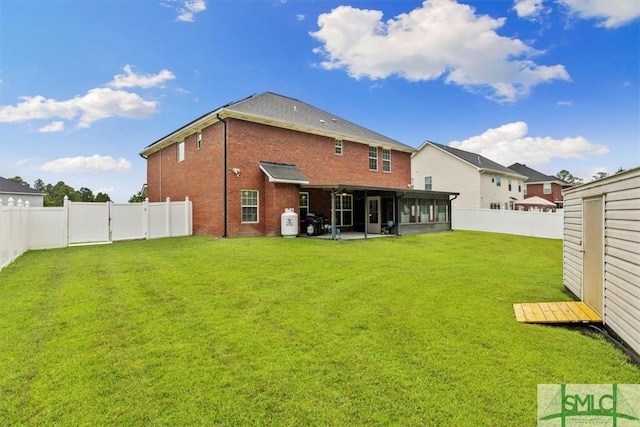 rear view of house with a yard, a storage shed, and a sunroom