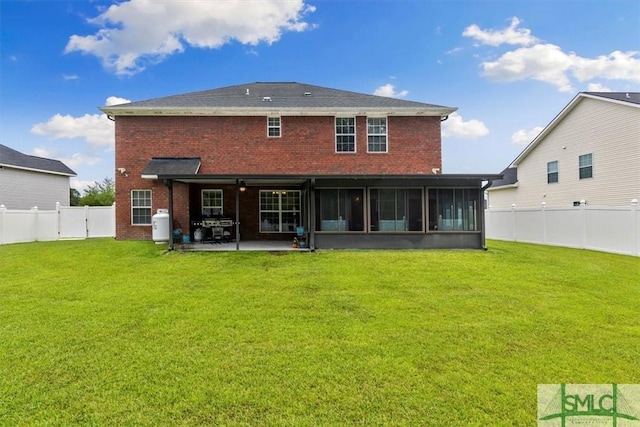 rear view of house featuring a lawn, a patio area, and a sunroom