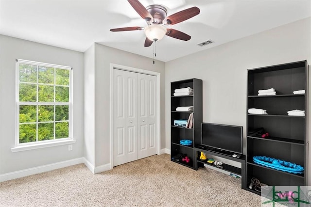 interior space with ceiling fan, light colored carpet, and a closet