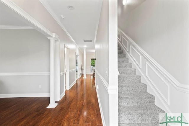 stairway with decorative columns, wood-type flooring, and ornamental molding