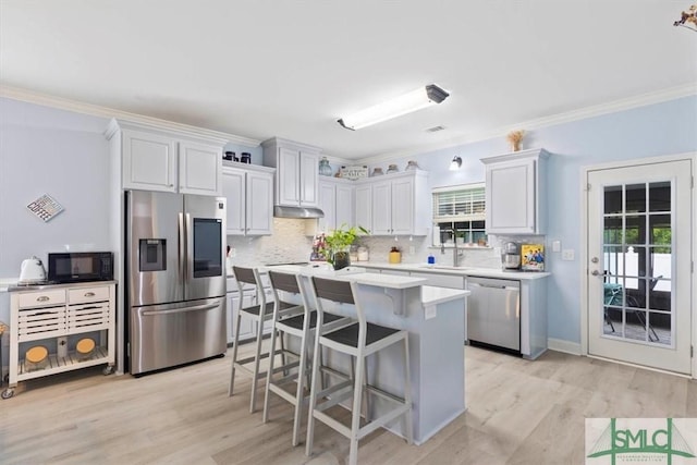 kitchen with white cabinetry, stainless steel appliances, crown molding, a breakfast bar, and sink