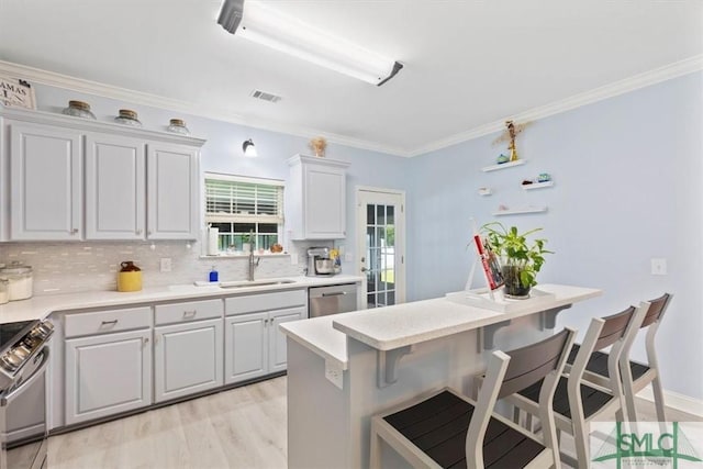 kitchen with stainless steel appliances, decorative backsplash, light wood-type flooring, a breakfast bar, and sink