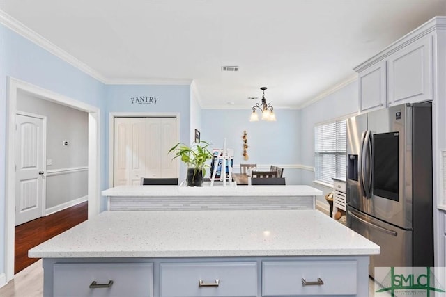 kitchen with stainless steel fridge with ice dispenser, crown molding, light hardwood / wood-style floors, and a center island