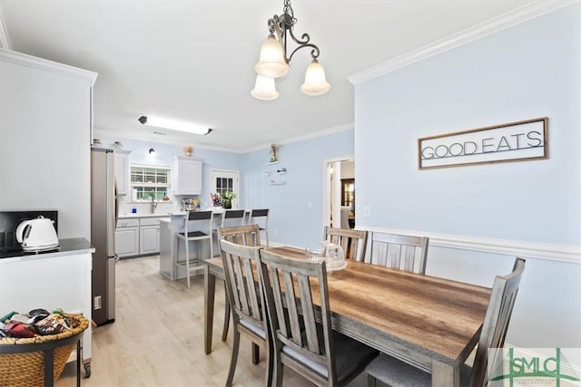 dining area with light hardwood / wood-style flooring, ornamental molding, and an inviting chandelier