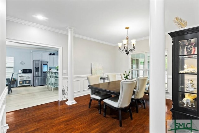 dining space with decorative columns, wood-type flooring, crown molding, and a chandelier