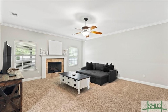 living room with ceiling fan, light colored carpet, a tiled fireplace, and ornamental molding