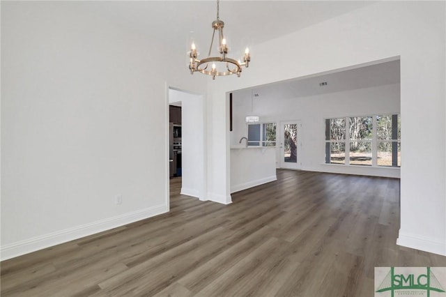 unfurnished living room featuring dark hardwood / wood-style floors, sink, and a chandelier