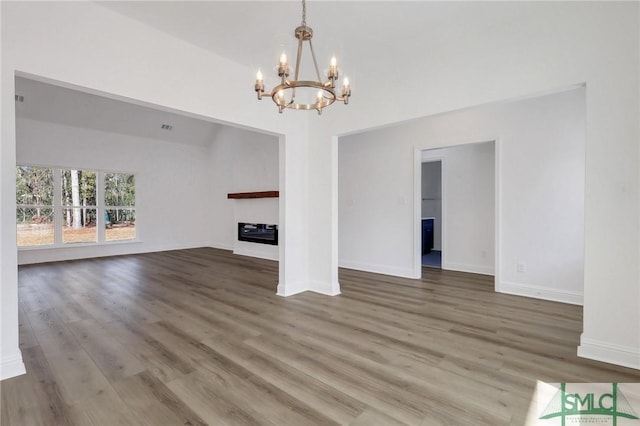 unfurnished living room with hardwood / wood-style flooring and a notable chandelier