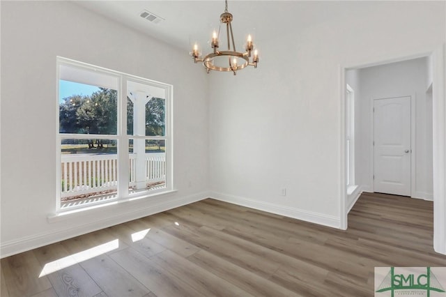 unfurnished dining area with wood-type flooring and an inviting chandelier