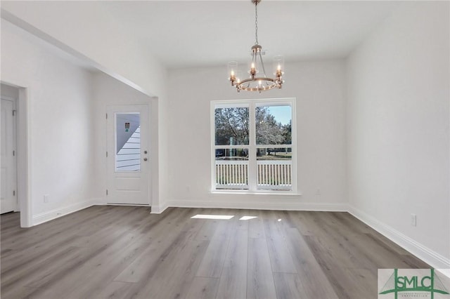 unfurnished dining area featuring a notable chandelier and wood-type flooring