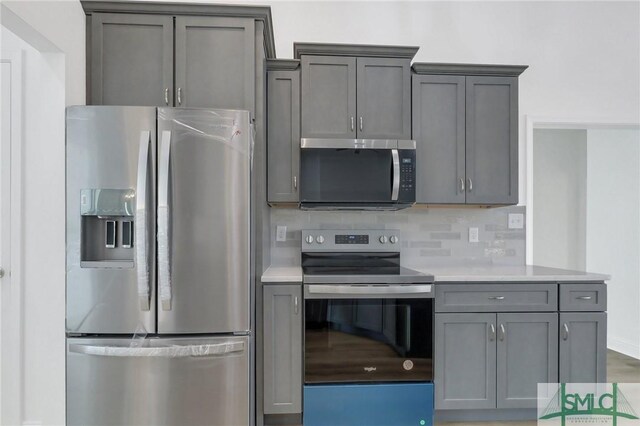 kitchen featuring backsplash, gray cabinetry, and stainless steel appliances