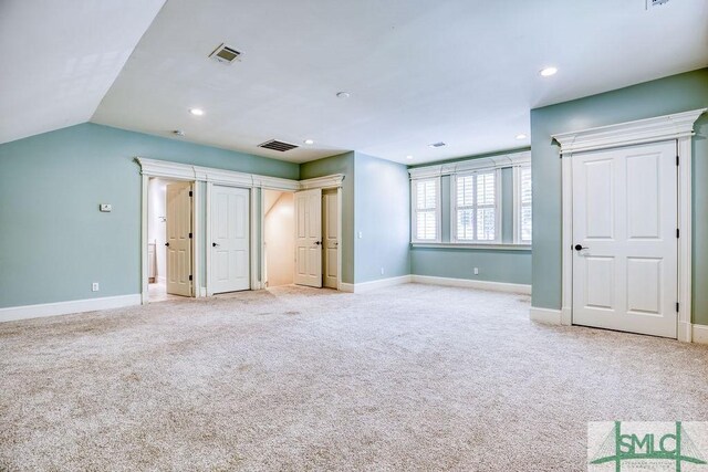 unfurnished bedroom featuring lofted ceiling and light colored carpet