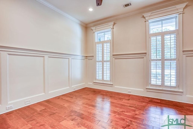 empty room featuring ornamental molding, a wealth of natural light, and light hardwood / wood-style floors