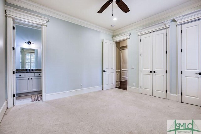 unfurnished bedroom featuring crown molding, ensuite bathroom, and light carpet