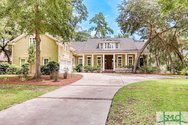 view of front of property with a garage, covered porch, and a front lawn