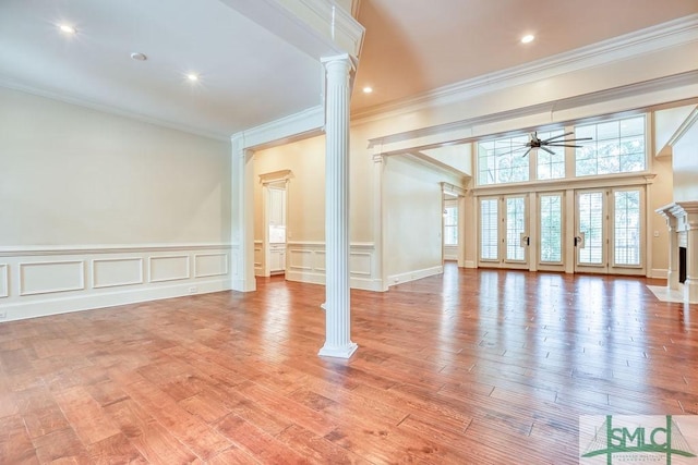 empty room featuring ornate columns, crown molding, ceiling fan, and light hardwood / wood-style flooring