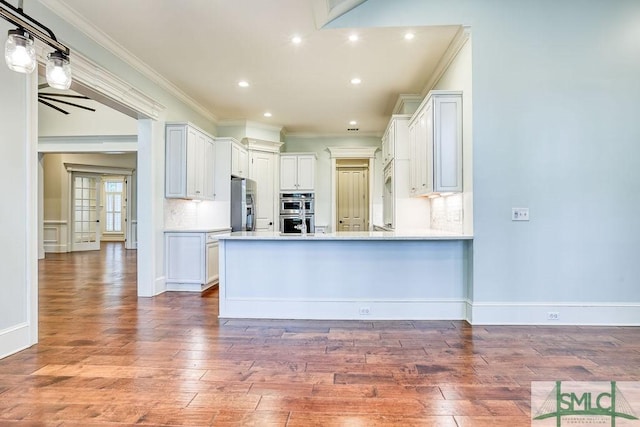 kitchen featuring crown molding, stainless steel appliances, kitchen peninsula, and white cabinets