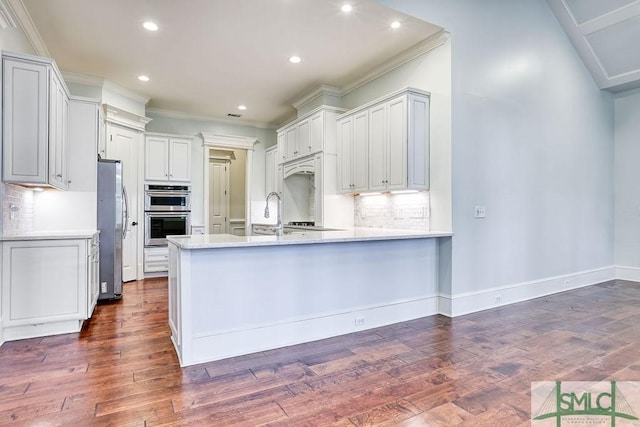 kitchen with white cabinetry, ornamental molding, dark hardwood / wood-style flooring, kitchen peninsula, and stainless steel appliances