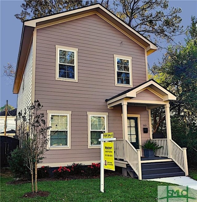 view of front of house with covered porch and a front lawn