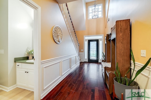 doorway to outside with a chandelier, wood-type flooring, and a towering ceiling