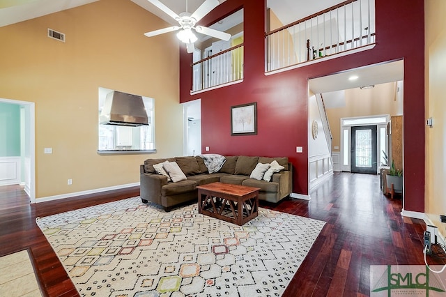 living room featuring ceiling fan, dark wood-type flooring, and a high ceiling