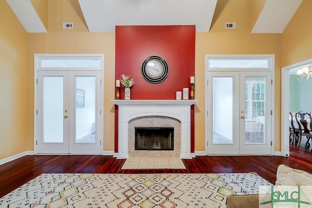 living room with a tile fireplace, french doors, wood-type flooring, and vaulted ceiling