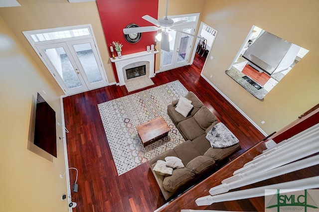 living room featuring dark wood-type flooring, a towering ceiling, french doors, and ceiling fan