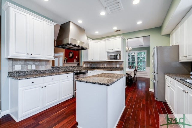 kitchen featuring tasteful backsplash, stainless steel appliances, white cabinets, wall chimney range hood, and dark wood-type flooring