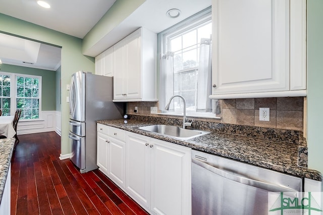 kitchen with appliances with stainless steel finishes, tasteful backsplash, hardwood / wood-style floors, sink, and white cabinetry