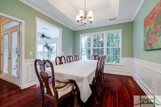 dining area featuring dark hardwood / wood-style floors, ceiling fan with notable chandelier, a raised ceiling, and ornamental molding