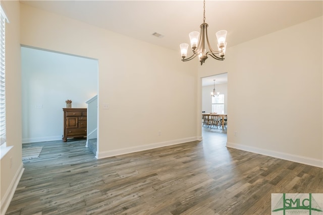 unfurnished room featuring an inviting chandelier and dark wood-type flooring