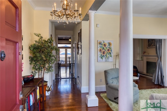 foyer entrance featuring decorative columns, dark wood-type flooring, and a notable chandelier