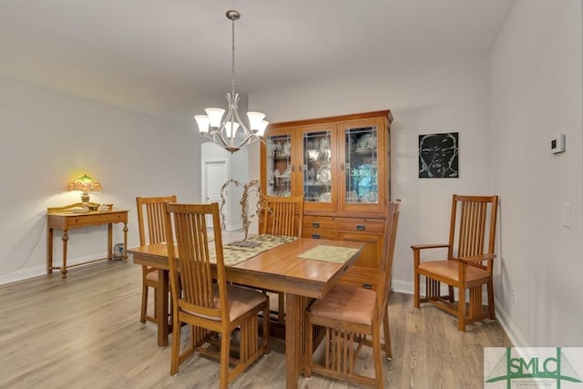 dining room with light hardwood / wood-style floors and an inviting chandelier