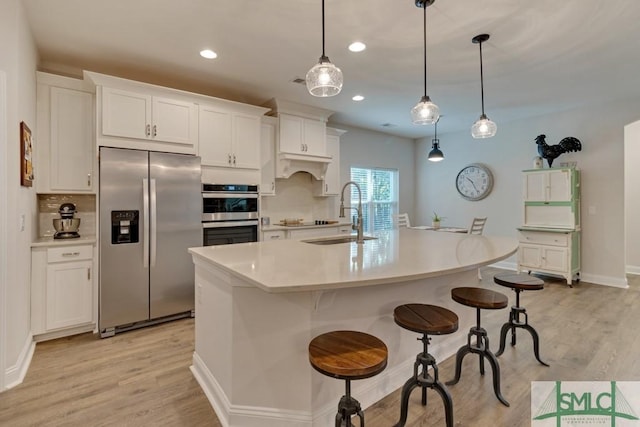 kitchen featuring sink, white cabinetry, stainless steel appliances, and hanging light fixtures