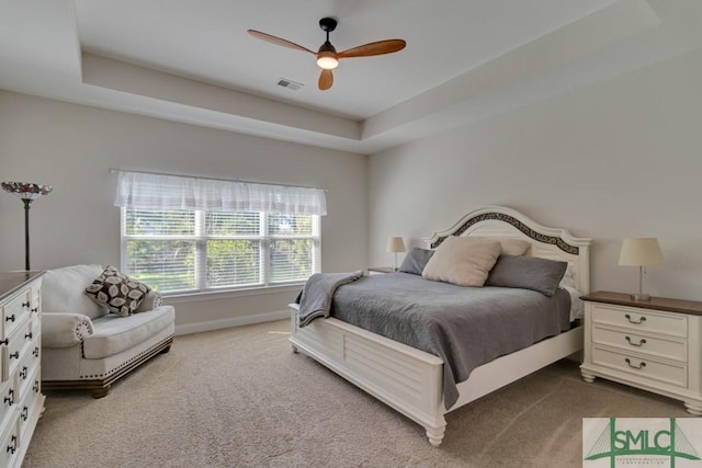 carpeted bedroom featuring ceiling fan and a raised ceiling