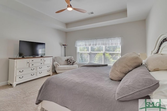 bedroom with light carpet, a raised ceiling, and ceiling fan