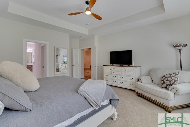 bedroom featuring carpet, connected bathroom, a tray ceiling, and ceiling fan