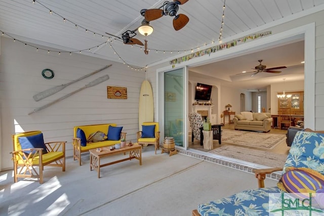 living room with wood walls, concrete floors, and ceiling fan with notable chandelier