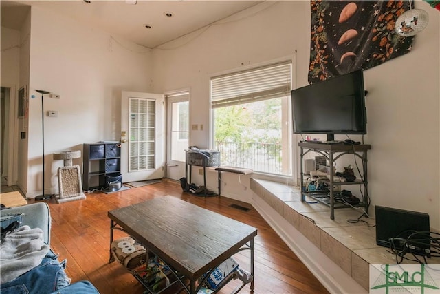 living room with a towering ceiling and wood-type flooring