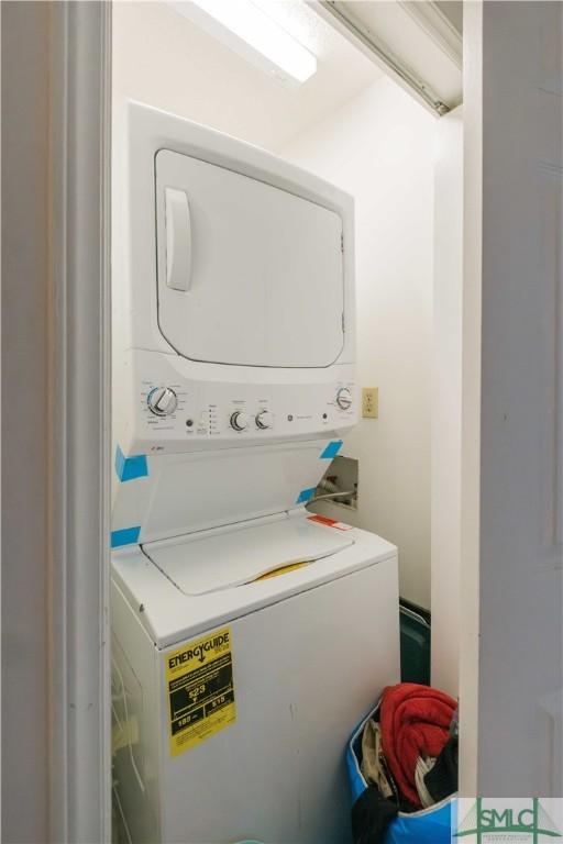 clothes washing area featuring stacked washer and clothes dryer