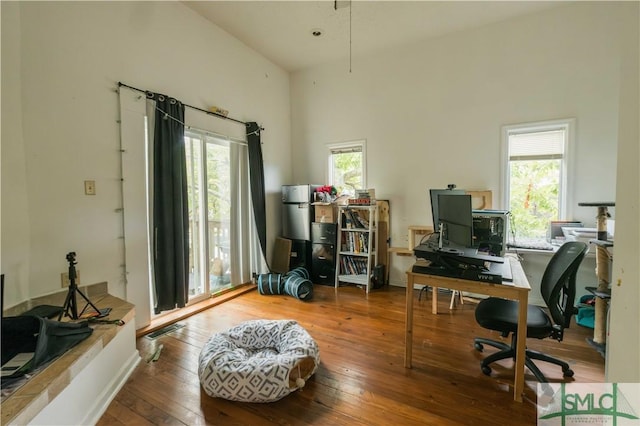 office area with hardwood / wood-style flooring and a towering ceiling