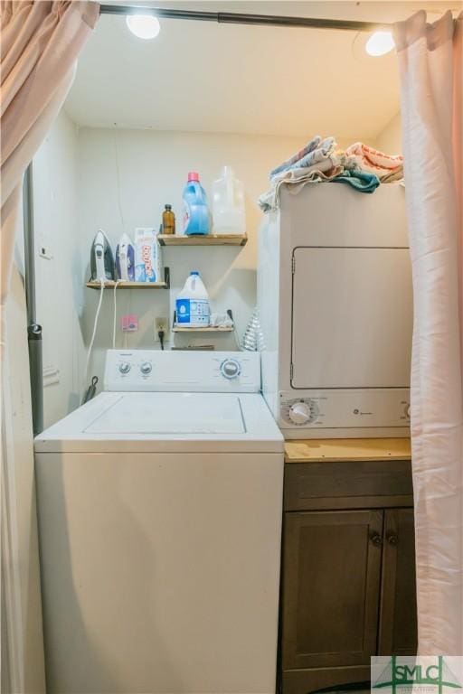 laundry room featuring stacked washer / drying machine and cabinets