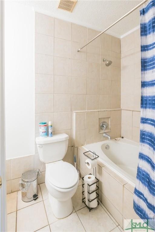 bathroom featuring shower / tub combo with curtain, toilet, a textured ceiling, tile walls, and tile patterned flooring