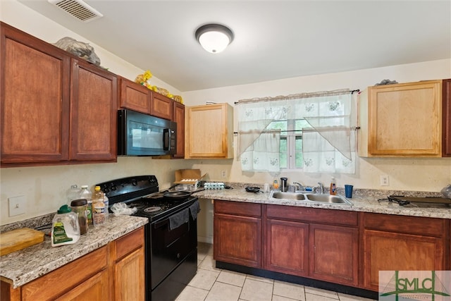 kitchen featuring sink, light stone countertops, black appliances, and light tile patterned floors