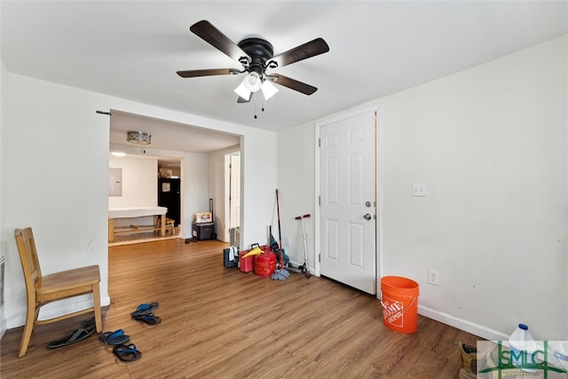 exercise area with wood-type flooring, electric panel, and ceiling fan