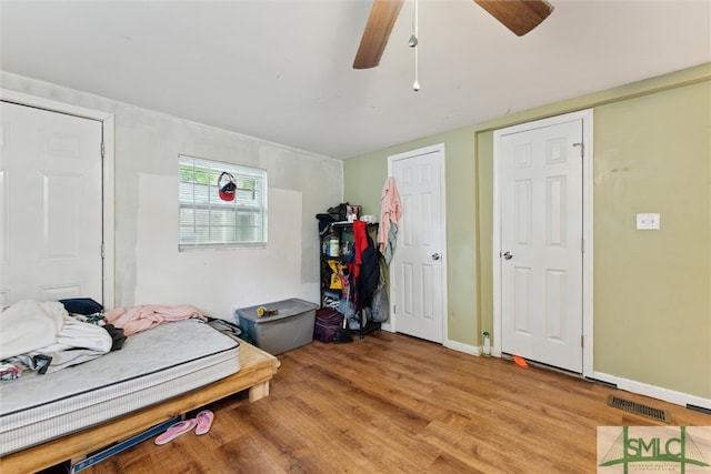 bedroom featuring light hardwood / wood-style floors, two closets, and ceiling fan