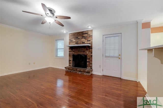 unfurnished living room featuring crown molding, a brick fireplace, dark hardwood / wood-style floors, and ceiling fan