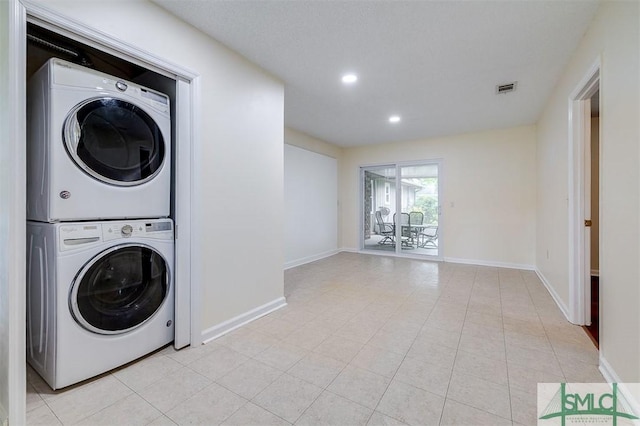 laundry area featuring light tile patterned floors and stacked washer and clothes dryer