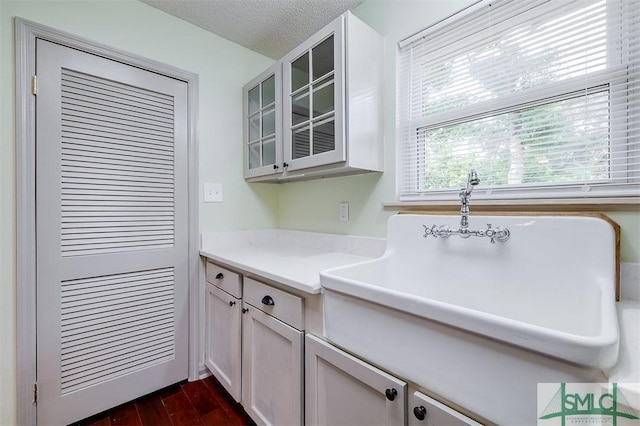 kitchen with dark hardwood / wood-style flooring, sink, a textured ceiling, and white cabinets