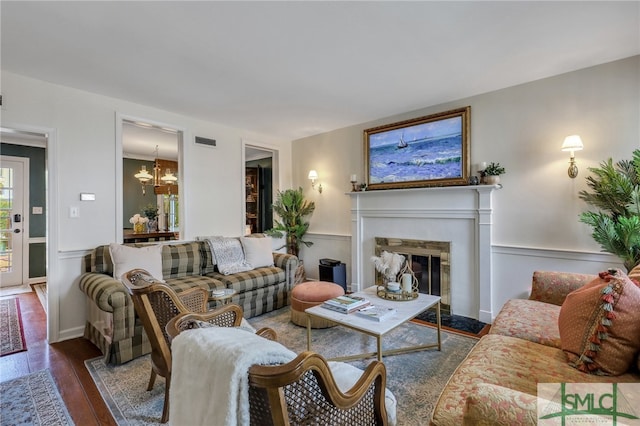 living room featuring a premium fireplace, dark wood-type flooring, and a chandelier